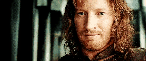 a man with long hair and a beard is looking at the camera with a serious look on his face .