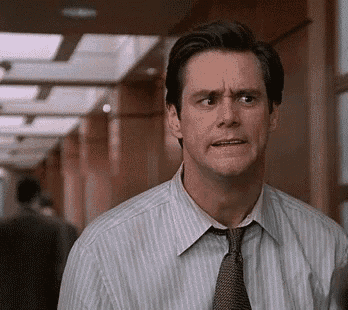 a man in a striped shirt and tie is standing in a hallway making a funny face .