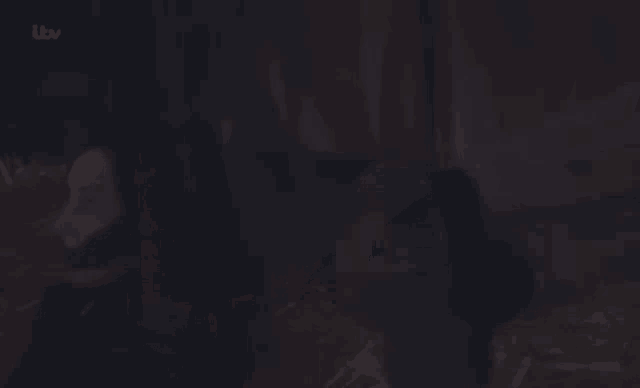 a person is sitting in a dark room with itv written on the bottom left corner .