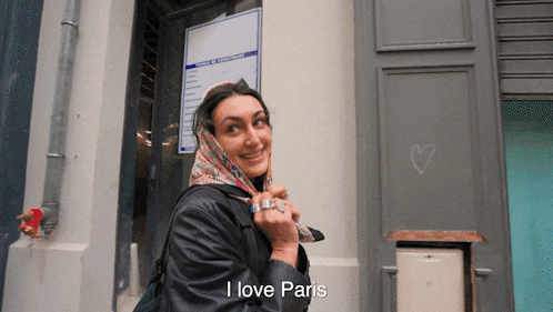 a woman wearing a scarf around her head is smiling and says i love paris