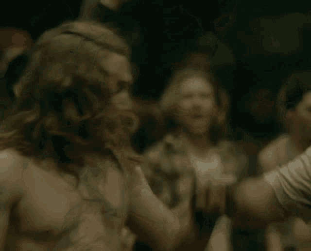 a man with long hair and a beard is standing in front of a crowd with his arms in the air .