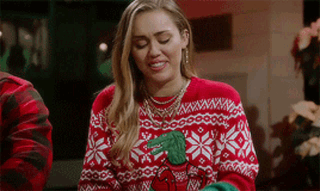 a woman wearing a red and white sweater with a green cactus on it