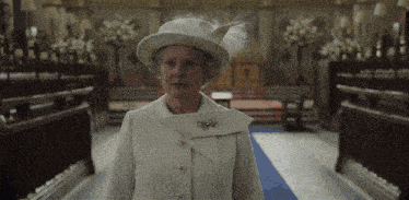 a woman wearing a white hat and a white coat stands in a church