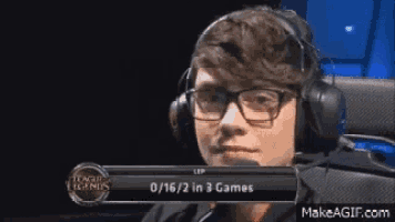 a man wearing headphones and glasses is playing league of legends .