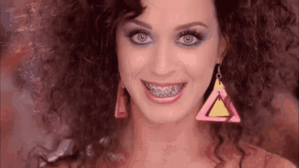 a woman wearing braces and earrings is smiling for the camera .