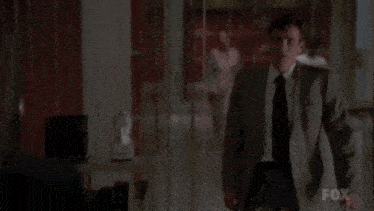 a man in a suit and tie is talking to another man in a hallway .