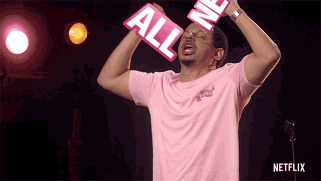 a man in a pink shirt is holding up a sign that says " all me "