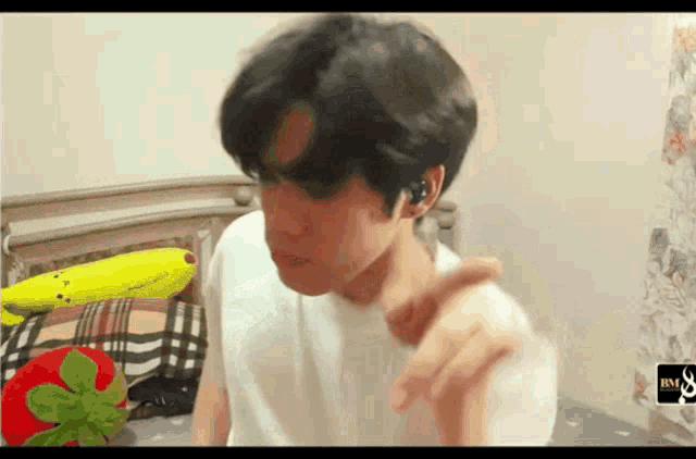 a man in a white shirt is sitting on a bed next to a banana