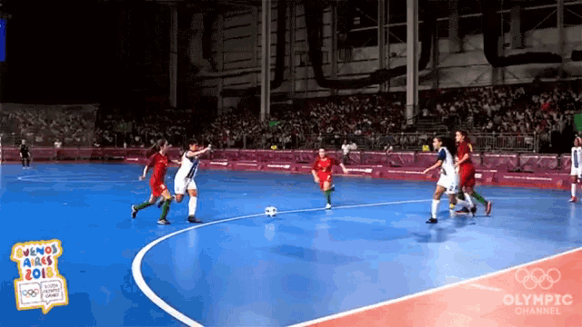 a group of soccer players on a blue court with the olympic channel logo in the corner