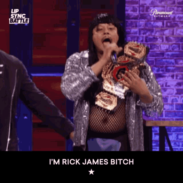 a man singing into a microphone with the words i 'm rick james bitch written below him