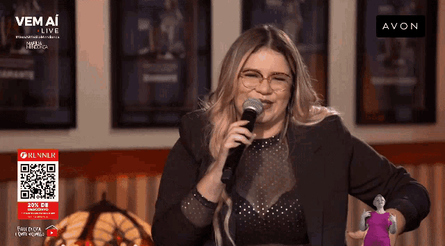 a woman singing into a microphone with the avon logo in the background