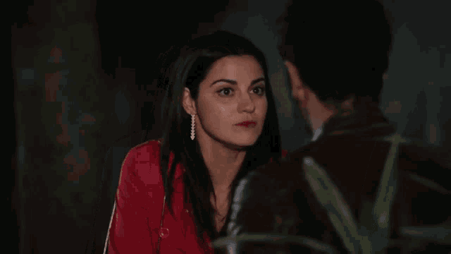 a woman in a red jacket looks at a man