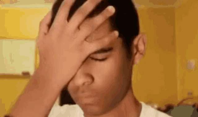a man is covering his face with his hand in a room .