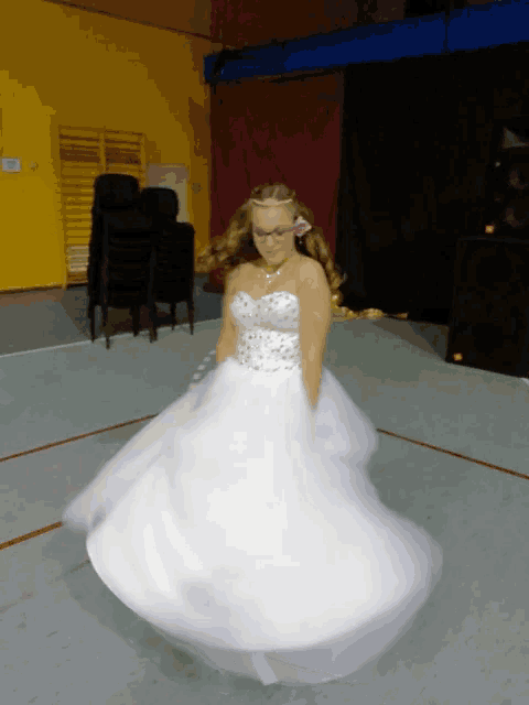 a girl in a white dress is dancing in a gym
