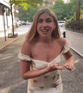 a woman in a floral dress is walking down a street .