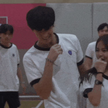 a boy in a white shirt with a blue circle on the front is smiling