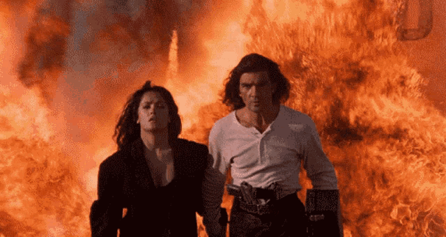 a man and woman standing in front of a fire