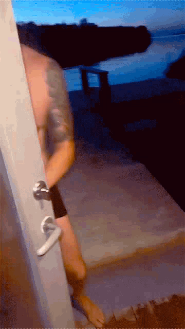 a man with a tattoo on his arm is standing in front of a door