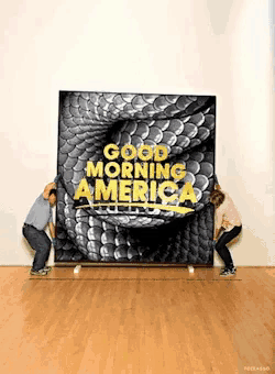 two people carrying a large poster that says good morning america on it