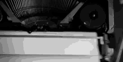 a black and white photo of a typewriter with a piece of paper being typed on it .