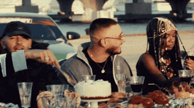 a group of people sitting around a table with a cake