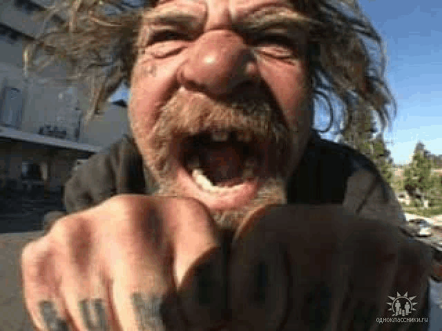 a man with a beard and mustache is pointing at the camera with his mouth wide open .