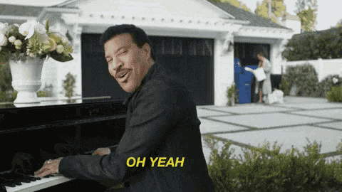 a man is playing a piano in front of a house and says oh yeah in yellow