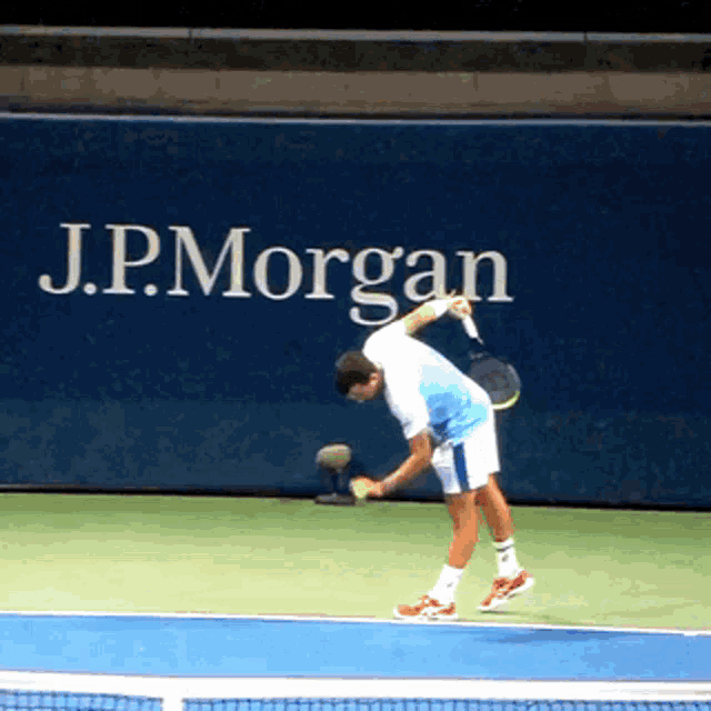 a man playing tennis in front of a j.p. morgan ad