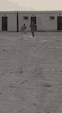 a person is holding a bird in their hand in front of a building in the desert .