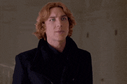a young man with red hair and green eyes is wearing a black coat and a black shirt .