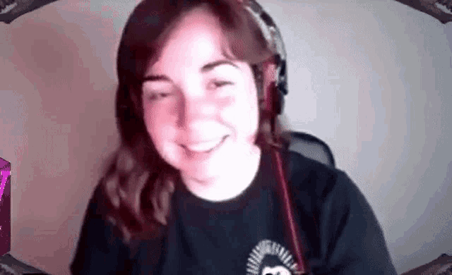 a woman wearing headphones and a black shirt is smiling while looking at the camera .