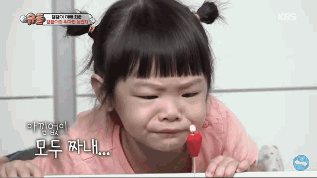 a little girl is crying while holding a red candle in her mouth