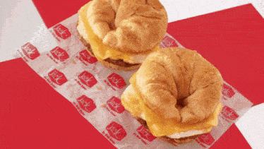 two jack in the box breakfast sandwiches are sitting on a piece of jack in the box paper