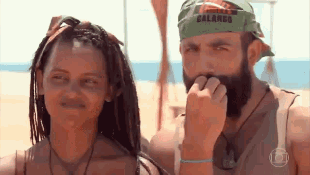 a man and a woman are standing next to each other on the beach .