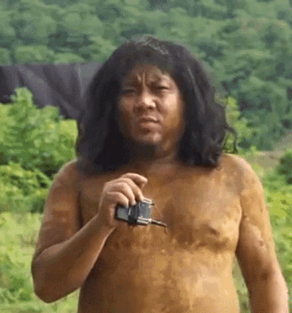 a naked man with long hair is holding a camera