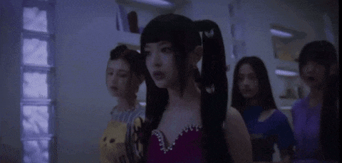 a group of women are standing in a room and one of them is wearing pigtails .