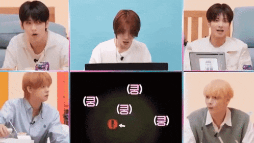 a group of young men are sitting in front of a computer screen with chinese characters on it .