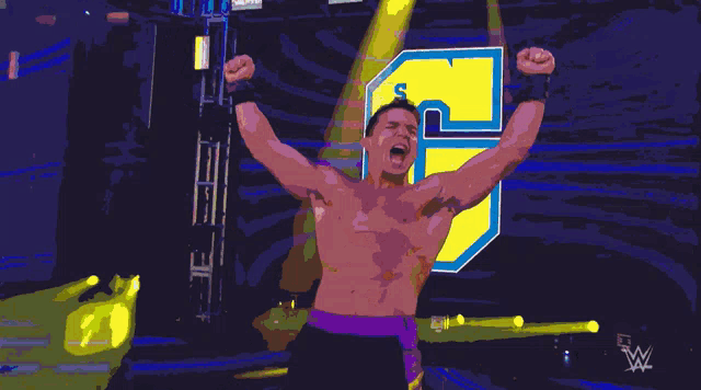 a shirtless wrestler with his arms in the air in front of the number 5