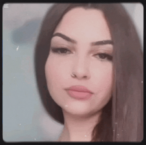 a close up of a woman 's face with long hair and a nose ring