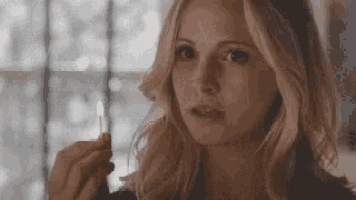 a woman is holding a lighter in her hand and looking at it .
