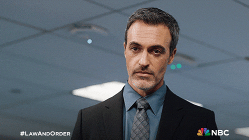 a man in a suit and tie stands in front of a sign that says law and order