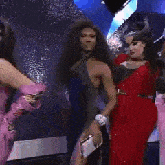 a group of drag queens are standing next to each other on a stage in a room .