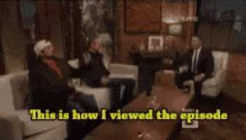 a man with a beard is sitting on a couch and says uh re-receiv-