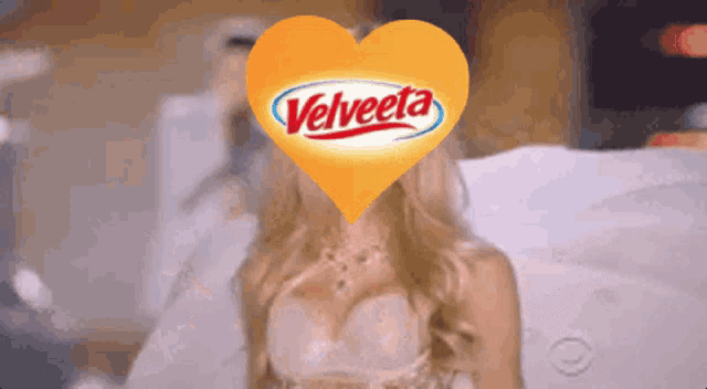 a woman 's face is covered by a yellow heart that says velveeta