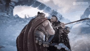 two men are standing next to each other in the snow holding a sword .