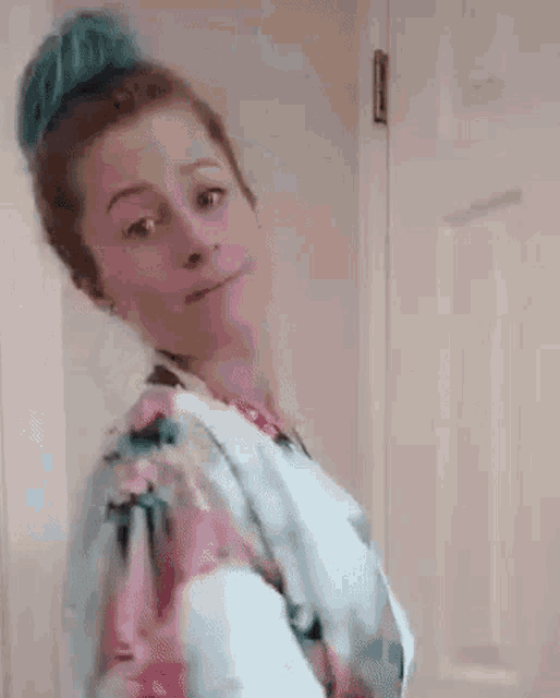 a woman in a floral robe is standing in a doorway .