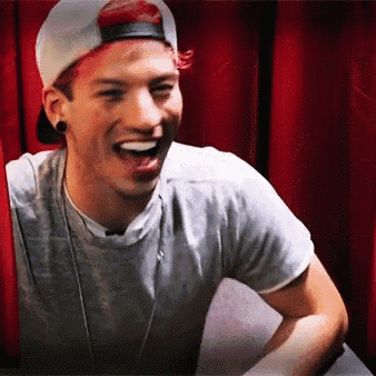 a man wearing a baseball cap and a gray shirt is laughing .