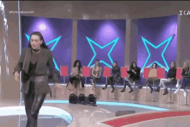 a woman is dancing on a stage in front of a purple background with stars