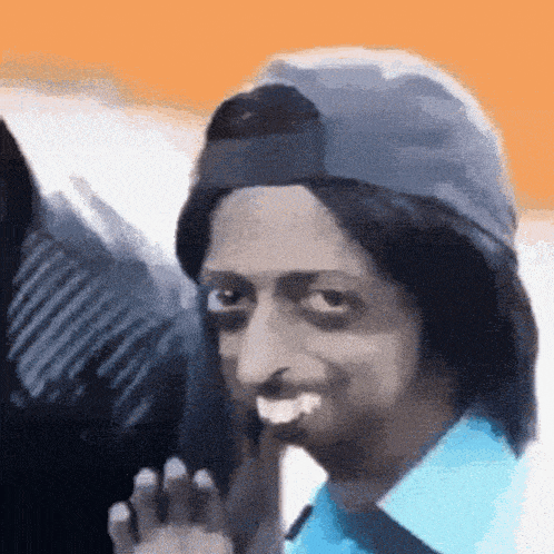 a man wearing a hat and a blue shirt is making a face