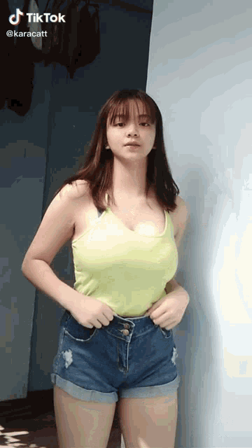 a woman in a yellow tank top and blue shorts has a tiktok sticker